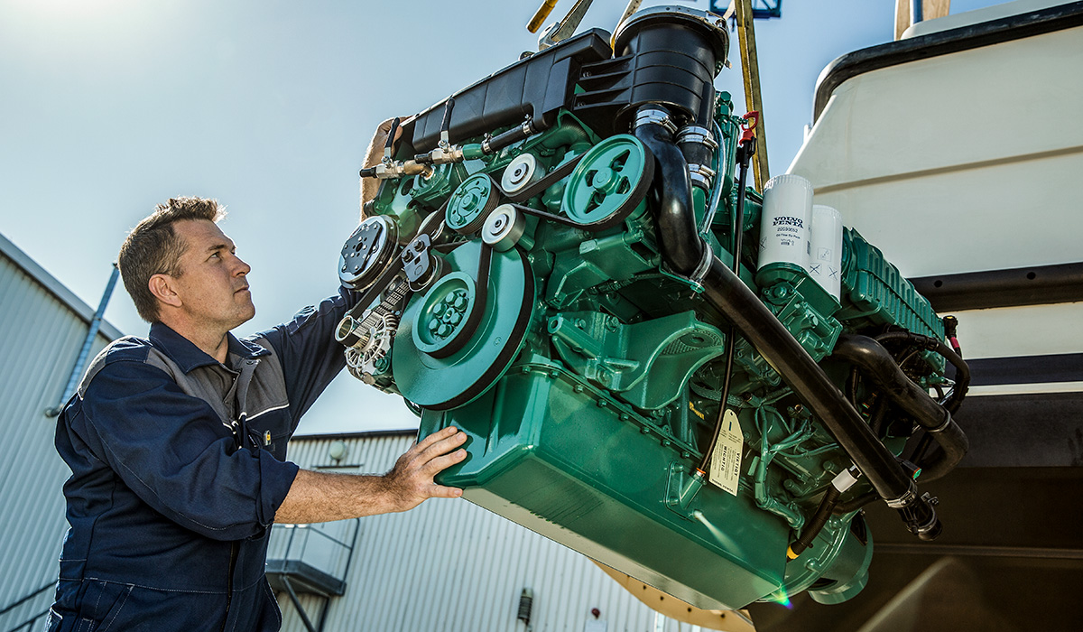 Photo of technician guiding Volvo Penta engine that is being lowered into a boat during a repower project